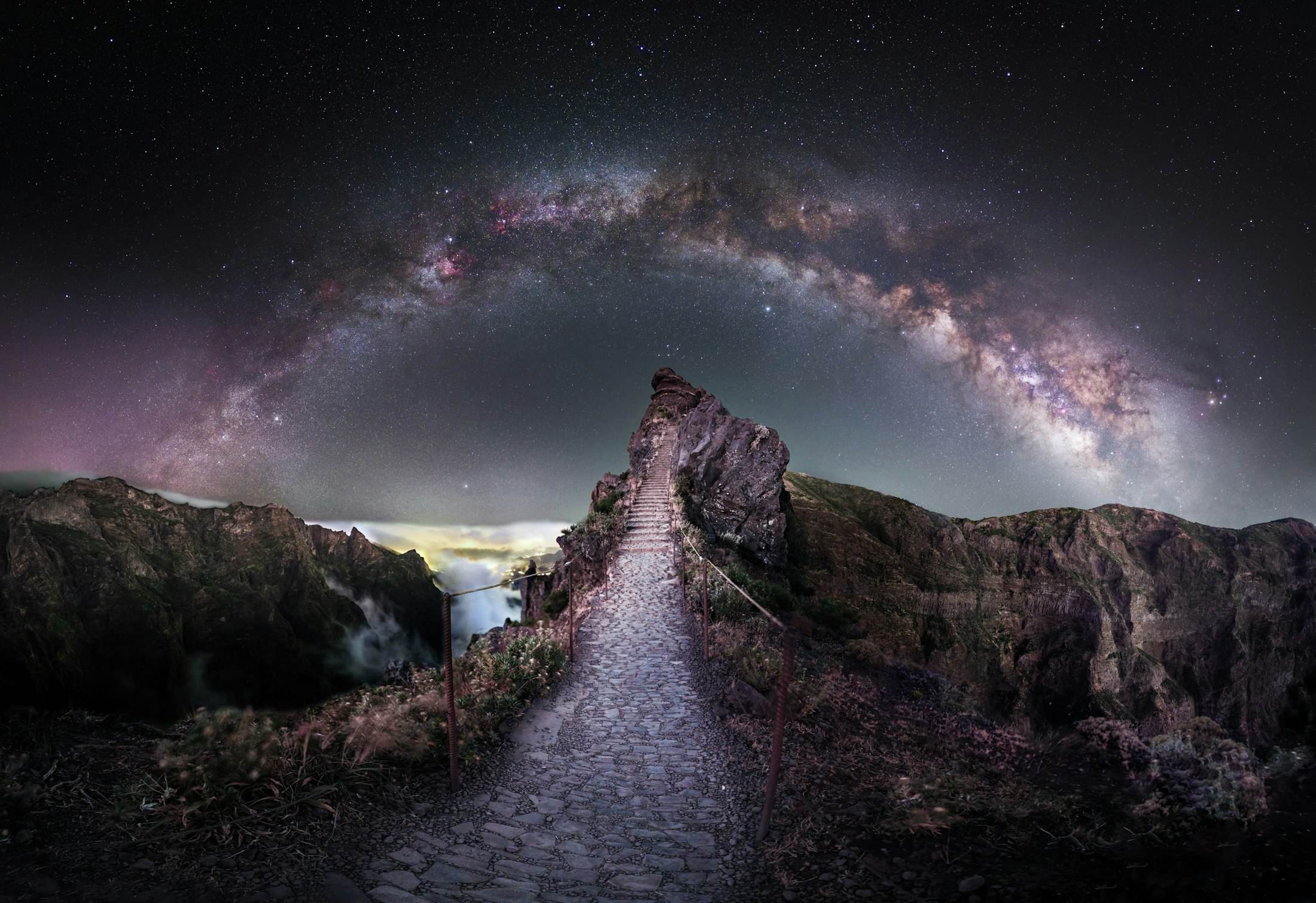 The Milky Way arching over a rocky mountain path at night